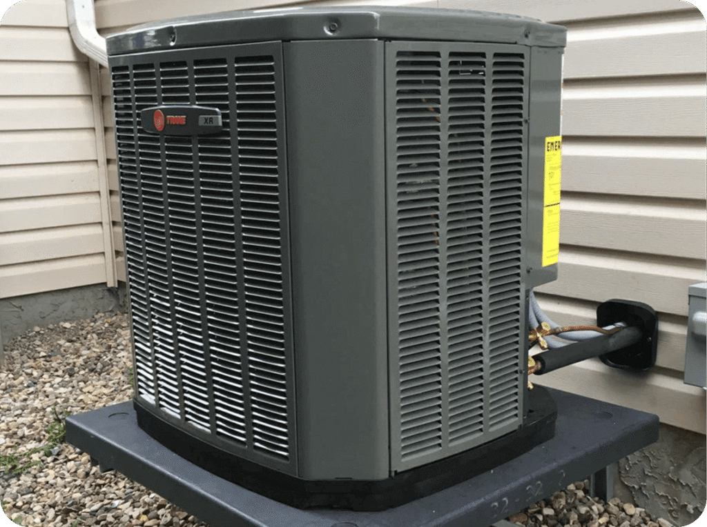 Outdoor Trane XR air conditioning unit on a metal platform outside a house with beige siding.