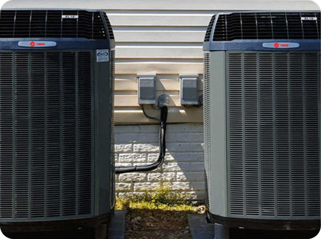 Two central air conditioning units outside a house, with power meters and conduit in between.