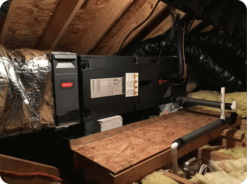 HVAC duct system installed in an attic with insulation on the floor and exposed wooden framing.
