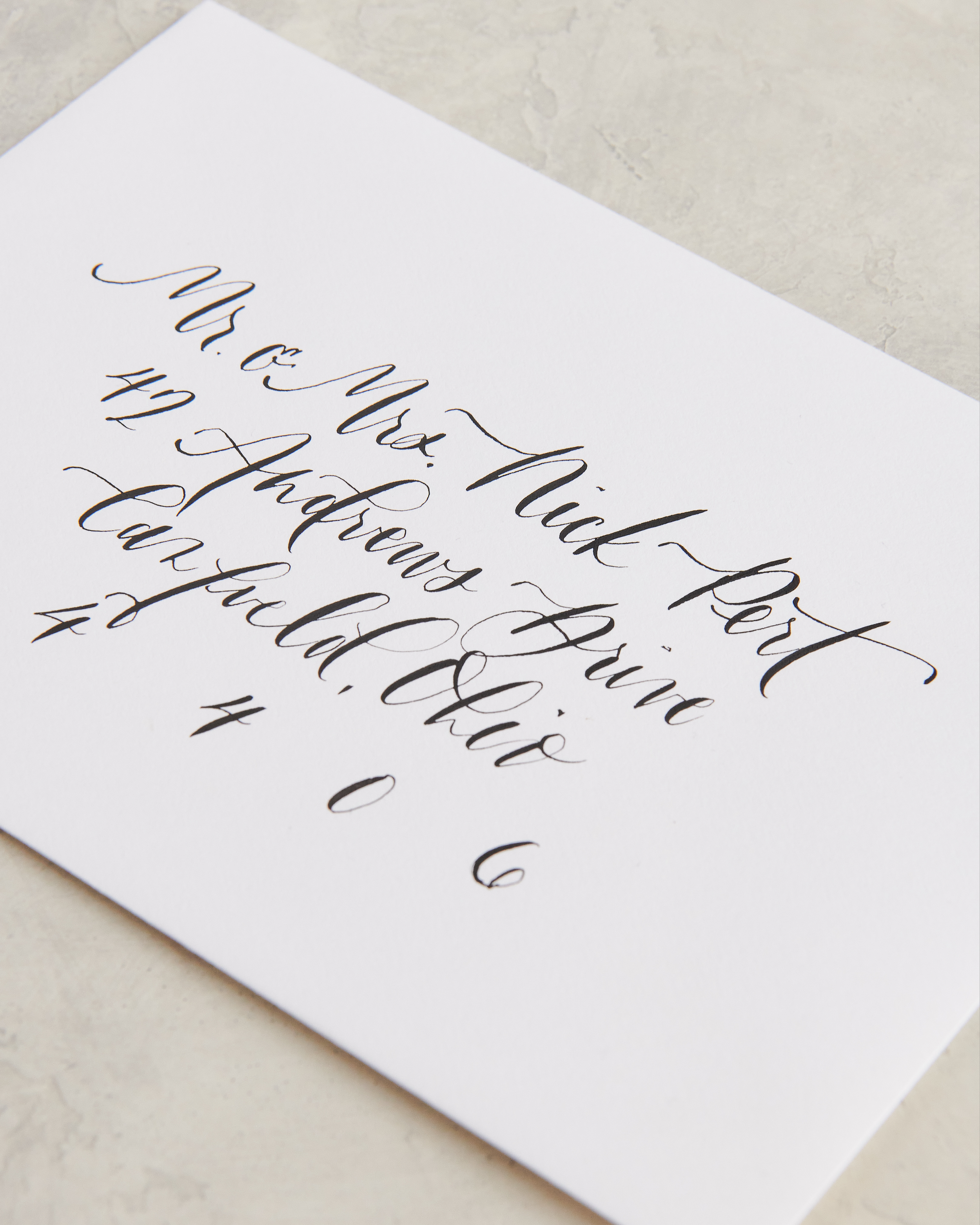 Close-up of white paper with black cursive handwriting on a light-colored surface.