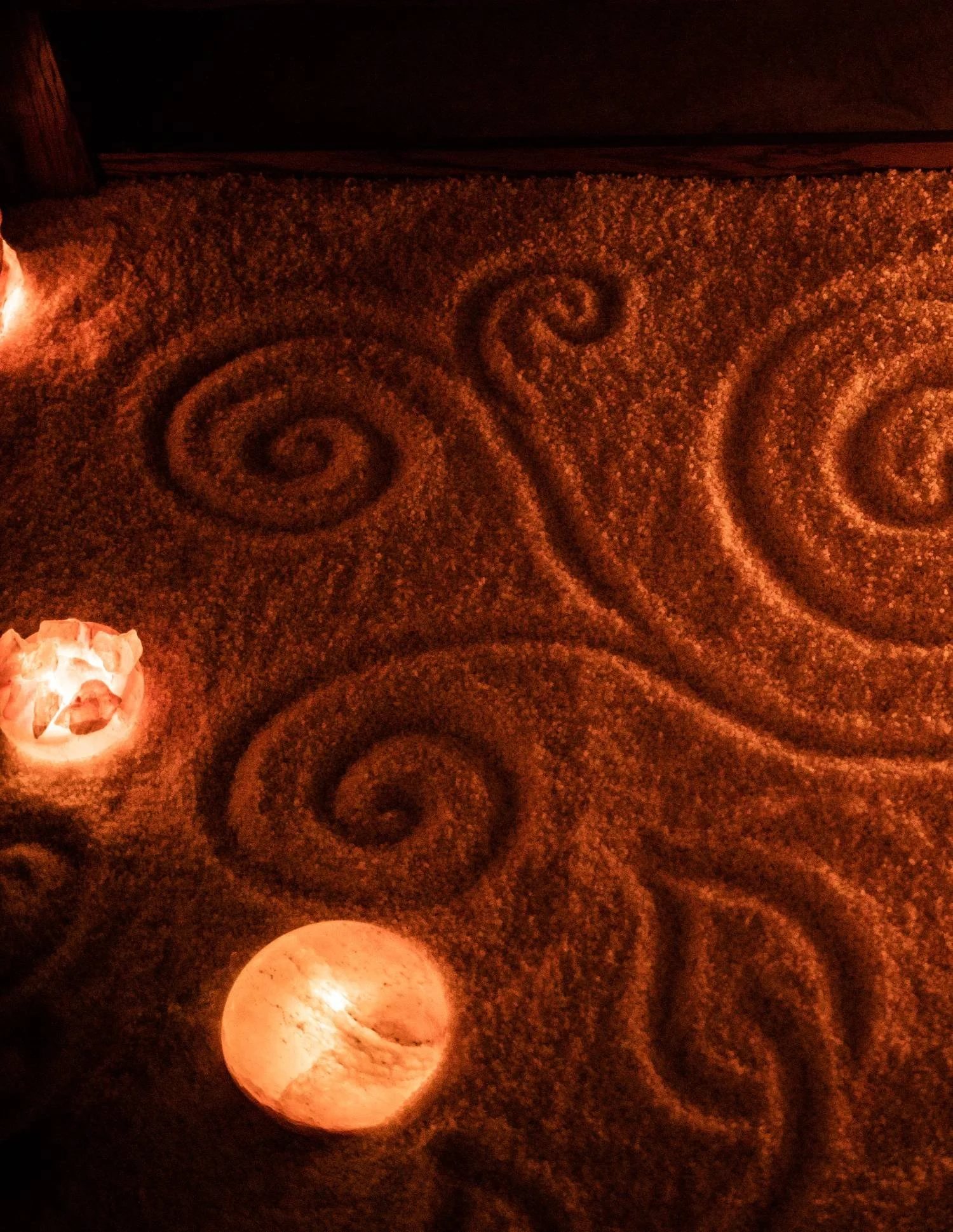 Dimly lit floor with a decorative, textured surface and three lit candles creating a warm ambiance.