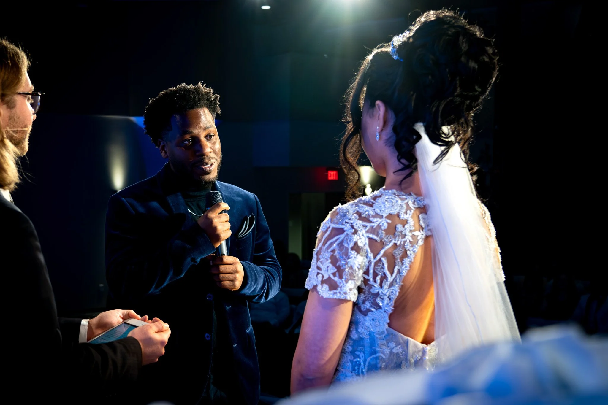 A couple getting married at a wedding ceremony, with the officiant speaking into a microphone.