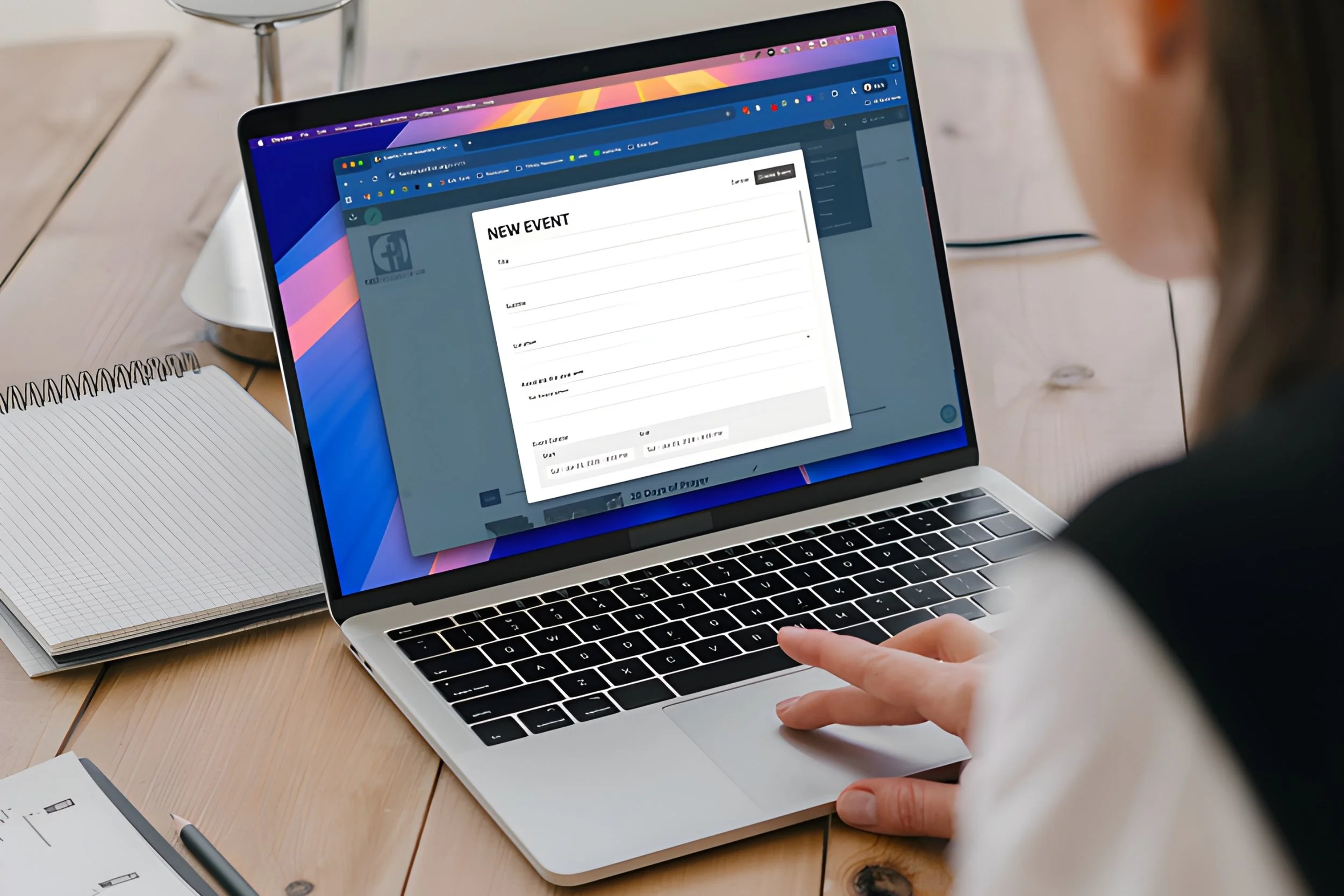A person using a MacBook laptop to create a new event in an online calendar or planning app.