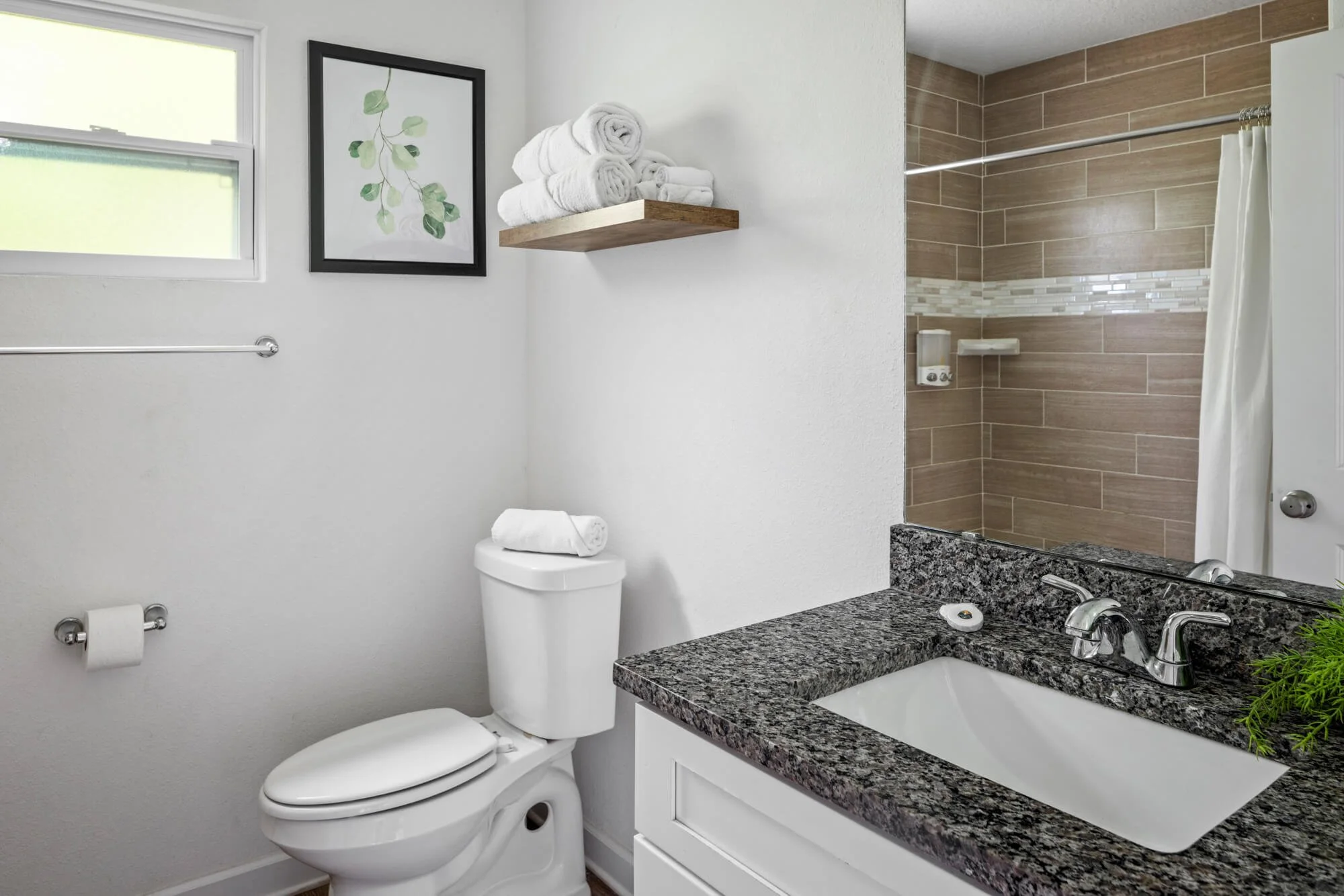 Bathroom with granite vanity, tiled shower, and fresh towels