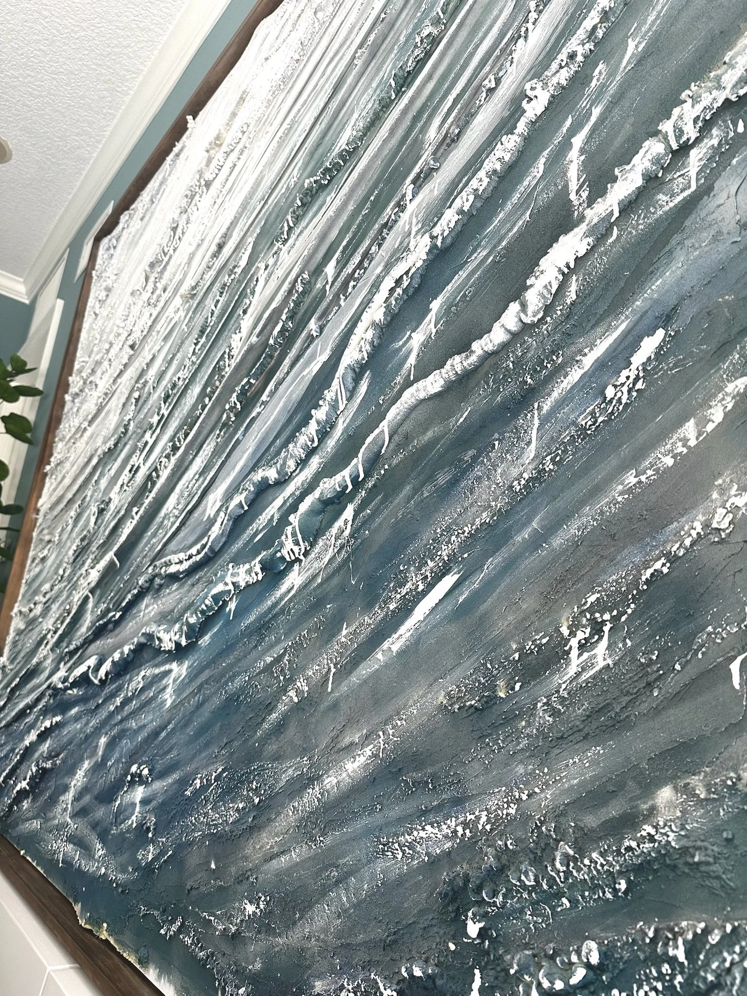 Close-up of a textured wall with metallic, abstract patterns in shades of silver, gray, and white.