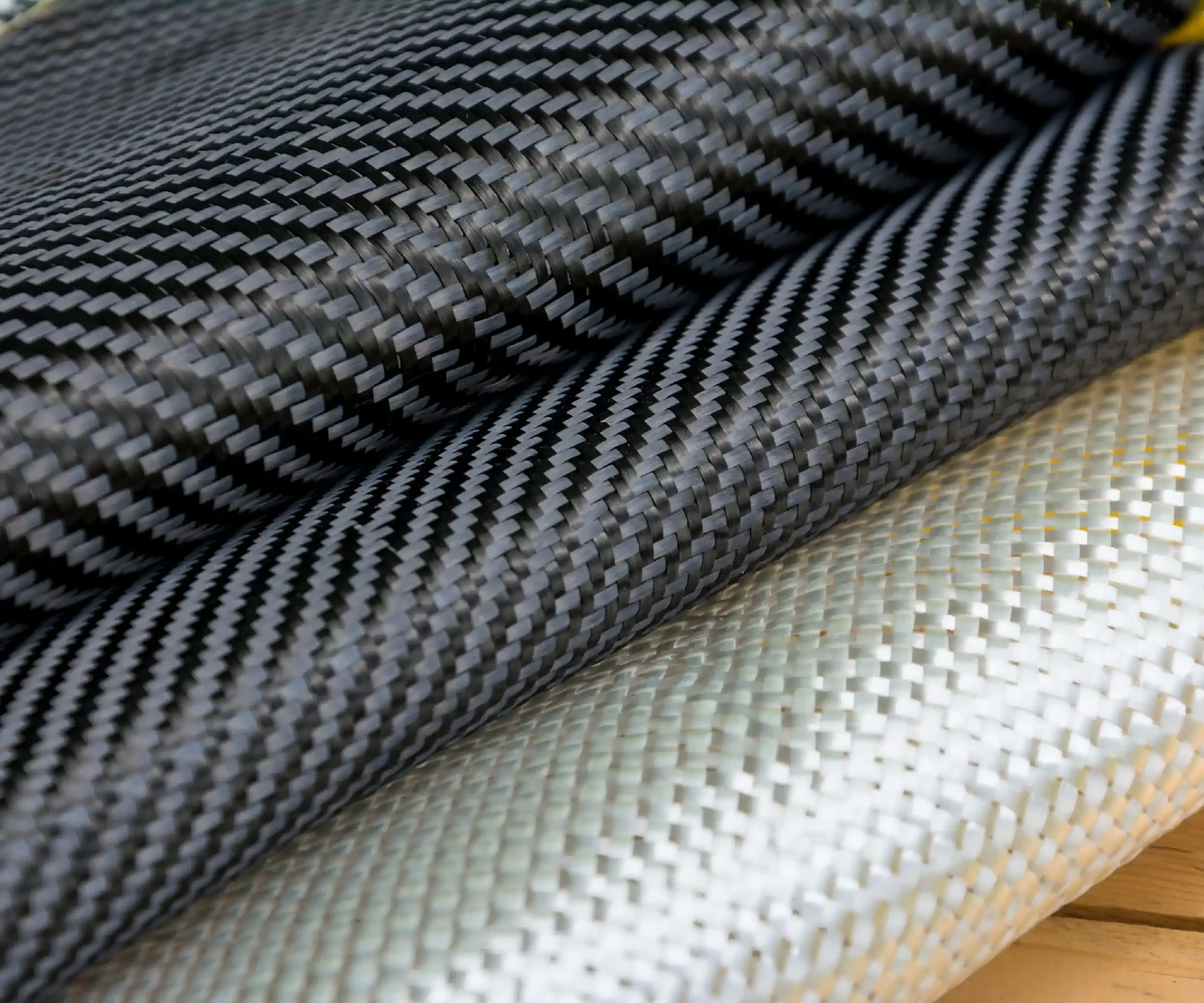 Close-up of a rolled-up woven black and gray carbon fiber fabric.