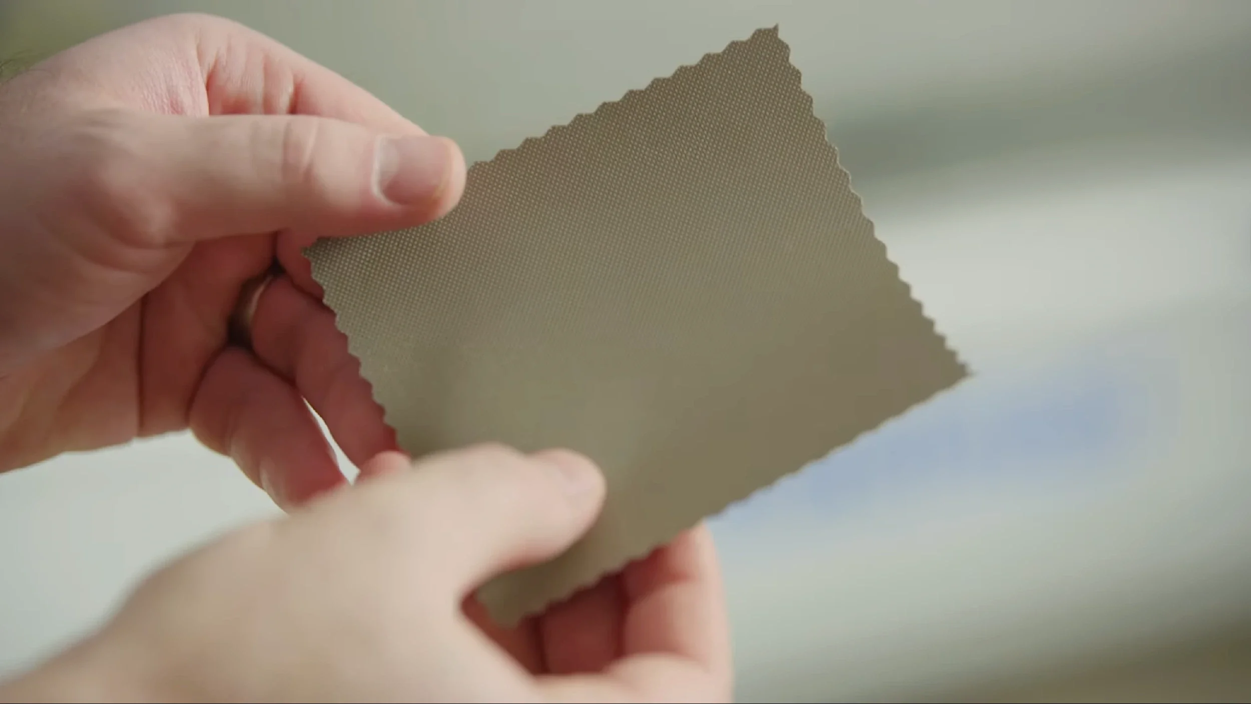 Close-up of hands holding a small cardboard piece with a jagged edge.