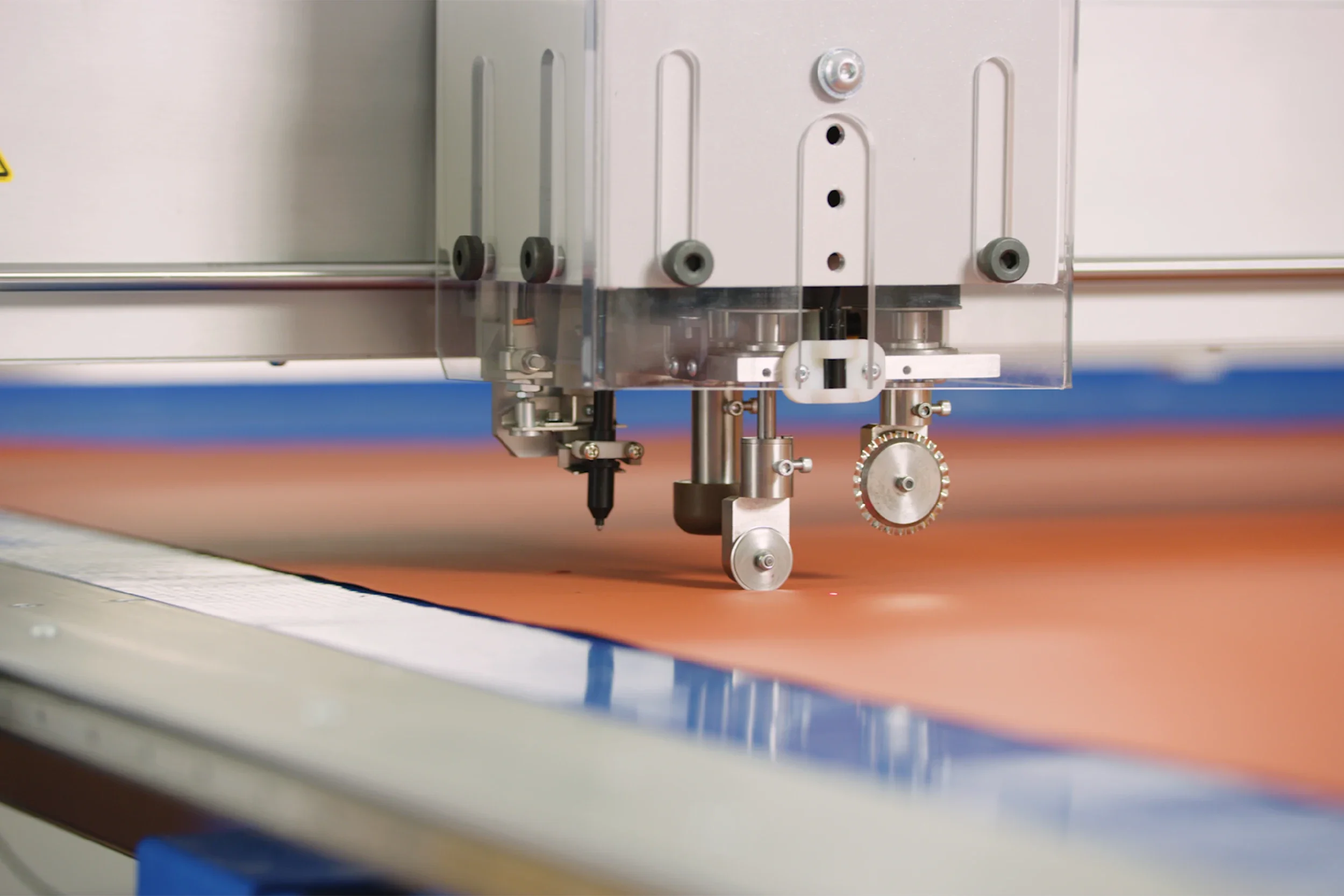 Close-up view of mechanical equipment with metal components, gears, and bolts, mounted above a table or work surface.
