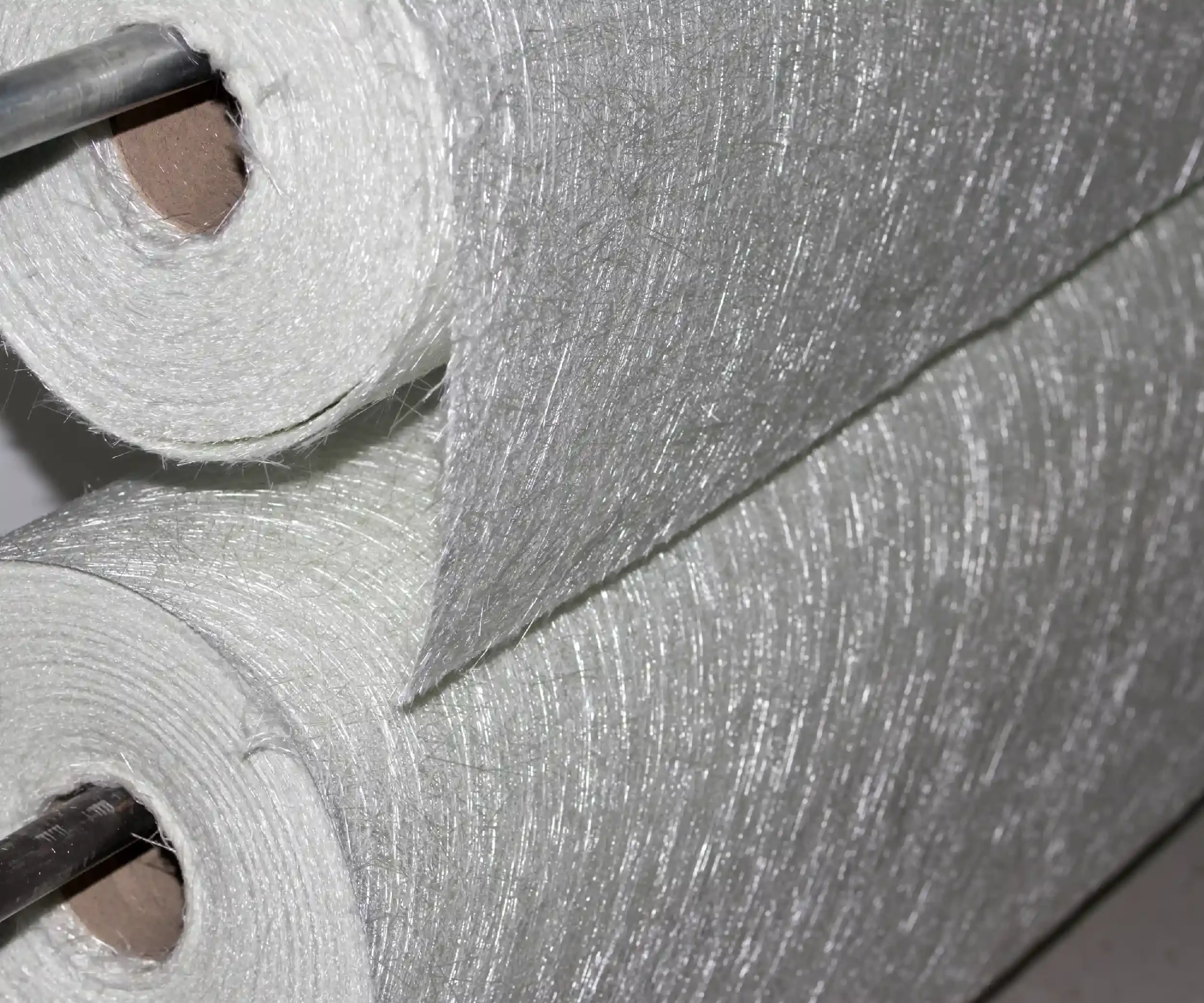 Close-up of a roll of white thread with a black needle partially visible at the bottom left, on a metallic surface.