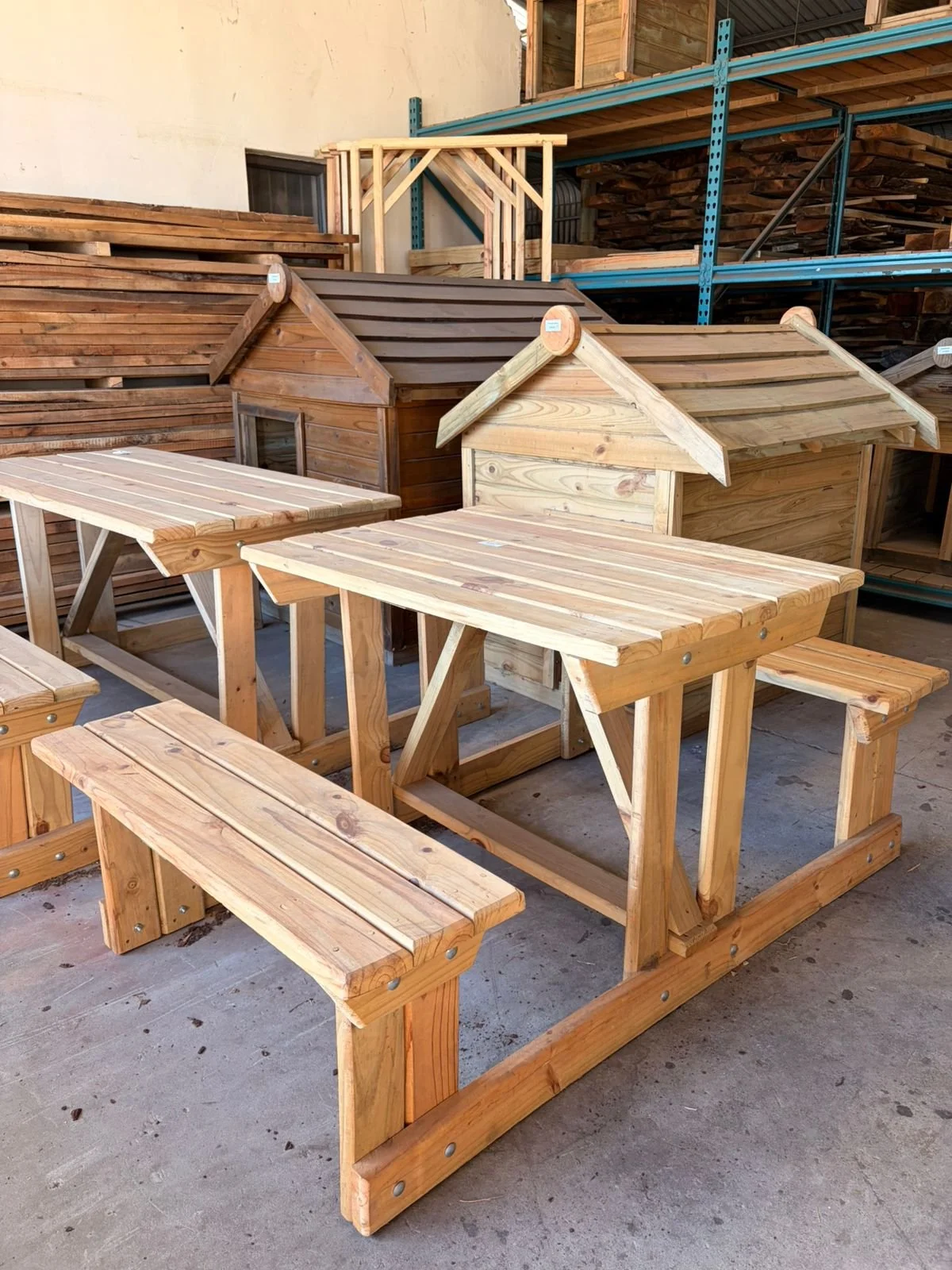 Wooden furniture including small benches, tables, and miniature houses displayed in a hardware store or workshop.