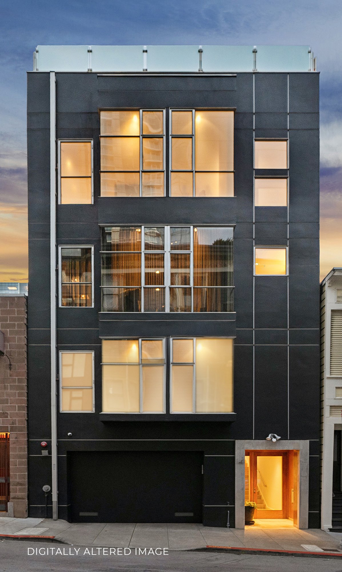 Modern multi-story building with large glass windows, some with warm interior lighting, and a black facade. The ground floor has a black garage door and illuminated entrance with a potted plant nearby. The sky has sunset hues.