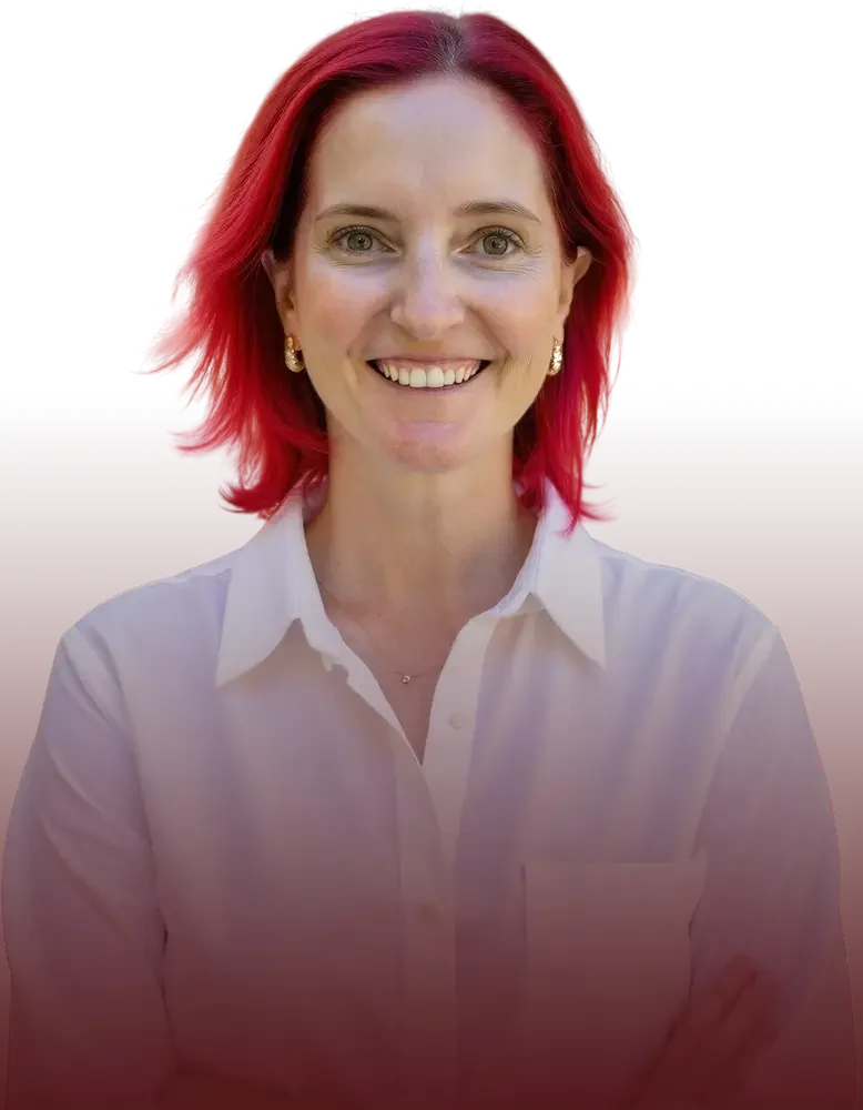 A woman with red hair smiling, wearing a white button-up shirt and gold earrings.