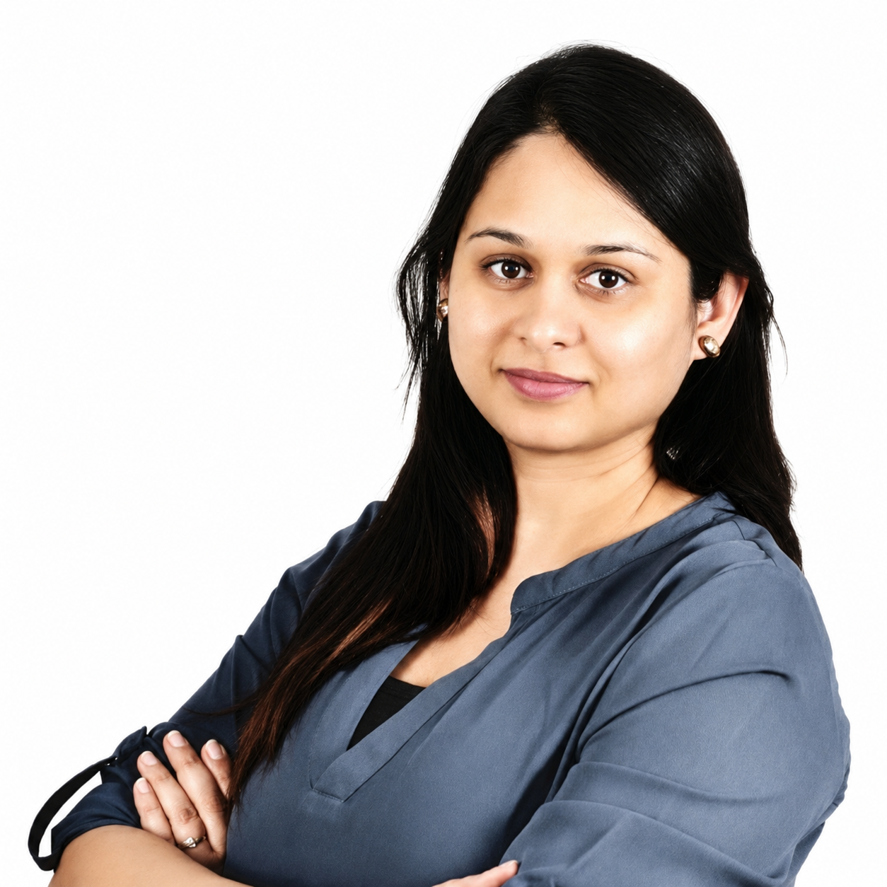 Professional woman with dark hair and earrings, wearing a navy scrub top, looking at the camera with a confident expression, arms crossed, against a white background.