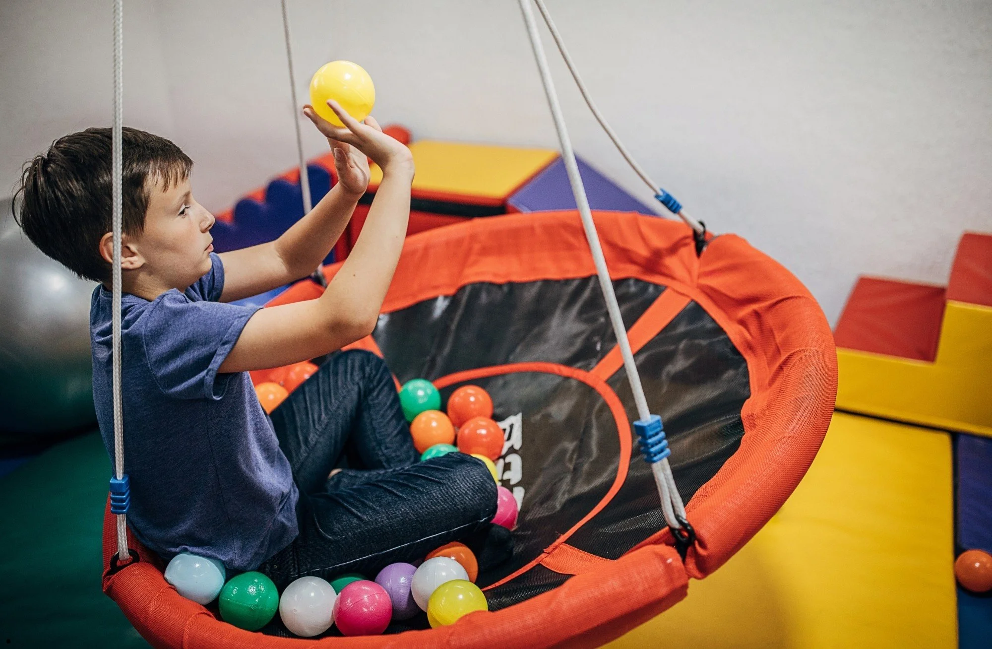 A child playing in a sensory saucer swing with colorful balls during an autism diagnostic assessment serving Forsyth County, North Carolina.
