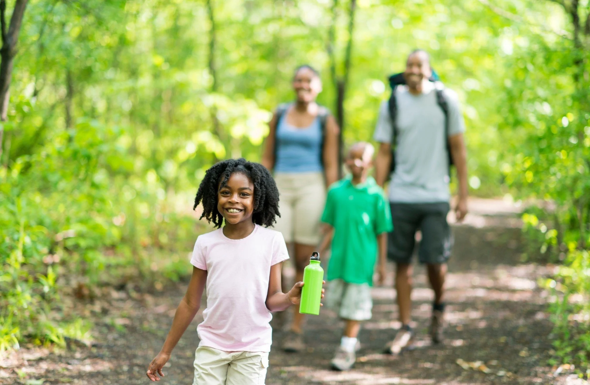 A happy family walking outdoors through a green forest, symbolizing the family-centered autism support provided by Evergreen Therapeutics in Thomasville, Davidson County, and Forsyth County, North Carolina.