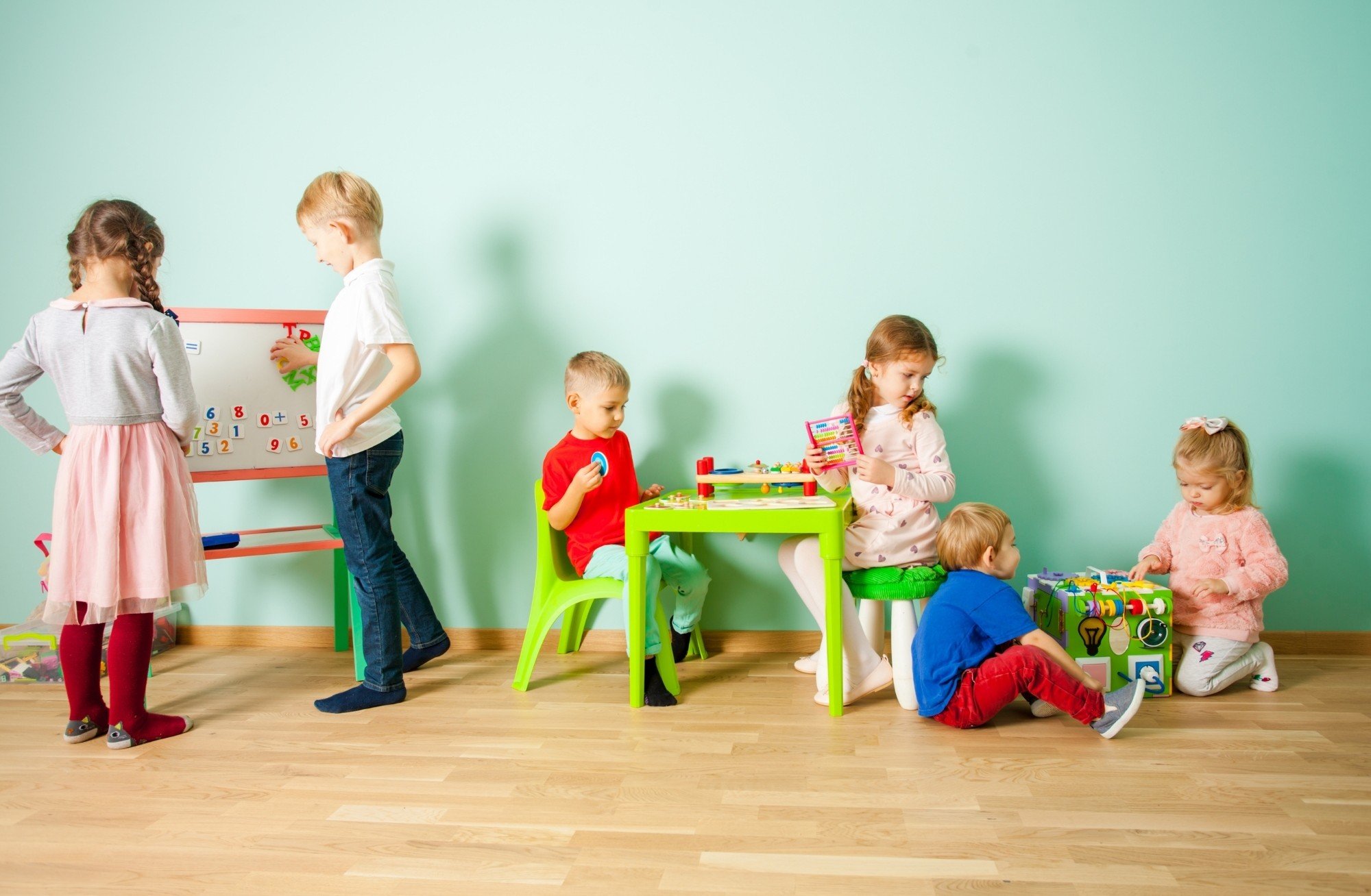 Young children and toddlers playing together with educational toys and a whiteboard during ABA therapy session serving Forsyth County, Davidson County, and Thomasville, North Carolina.