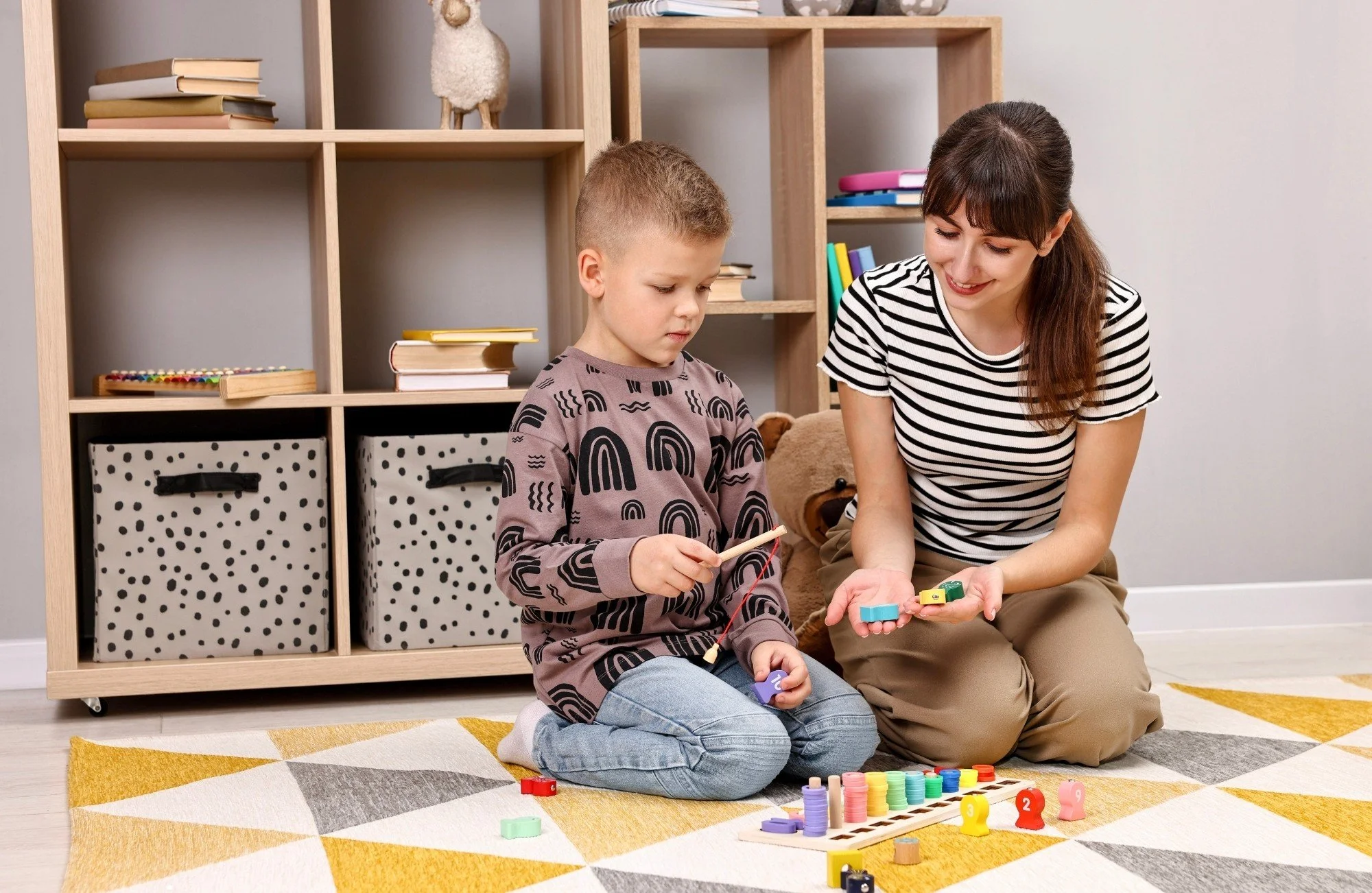 A therapist and young boy playing with educational wooden sorting toys during an individualized ABA therapy session in Thomasville, NC.