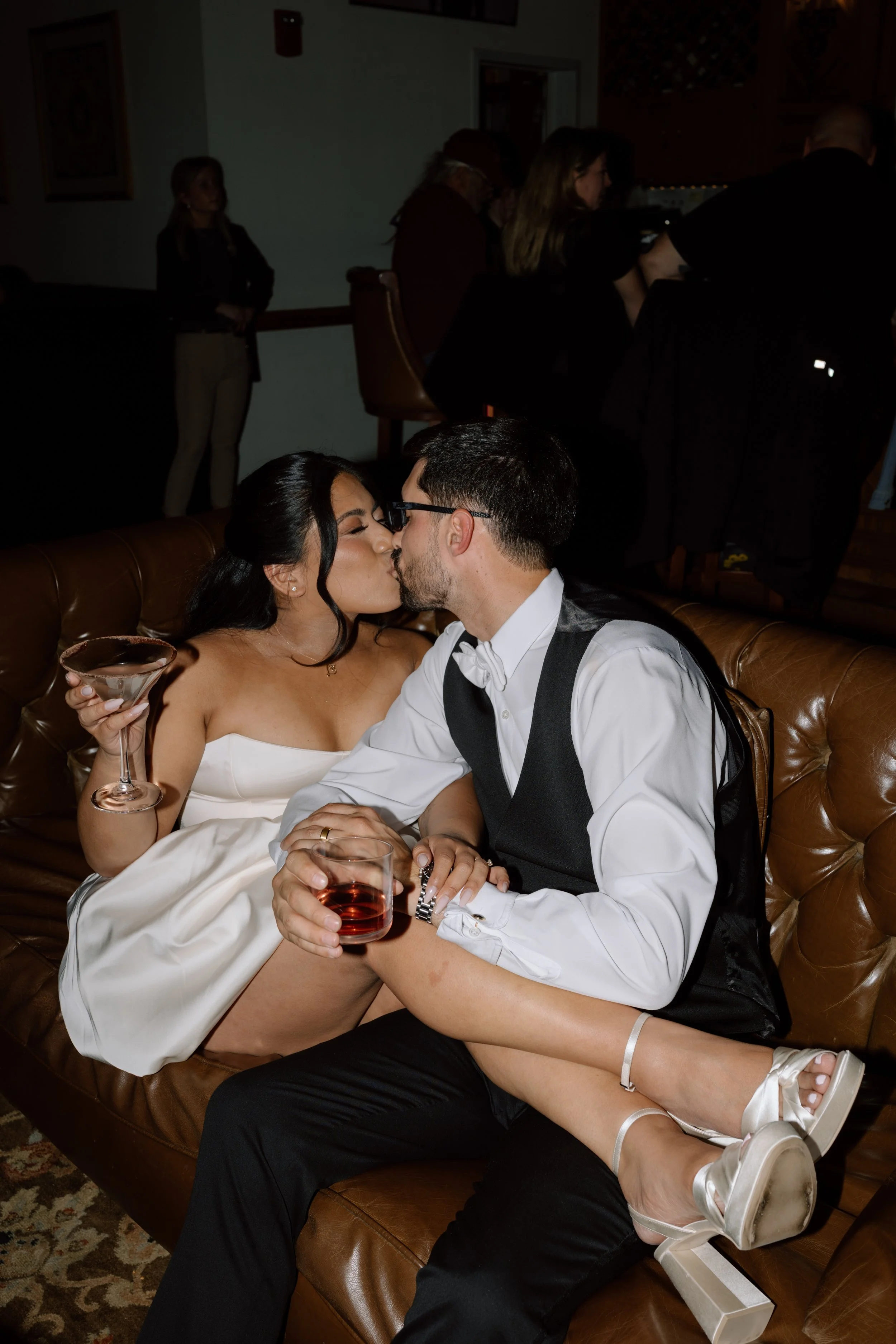 bride and groom kissing on sofa with drinks