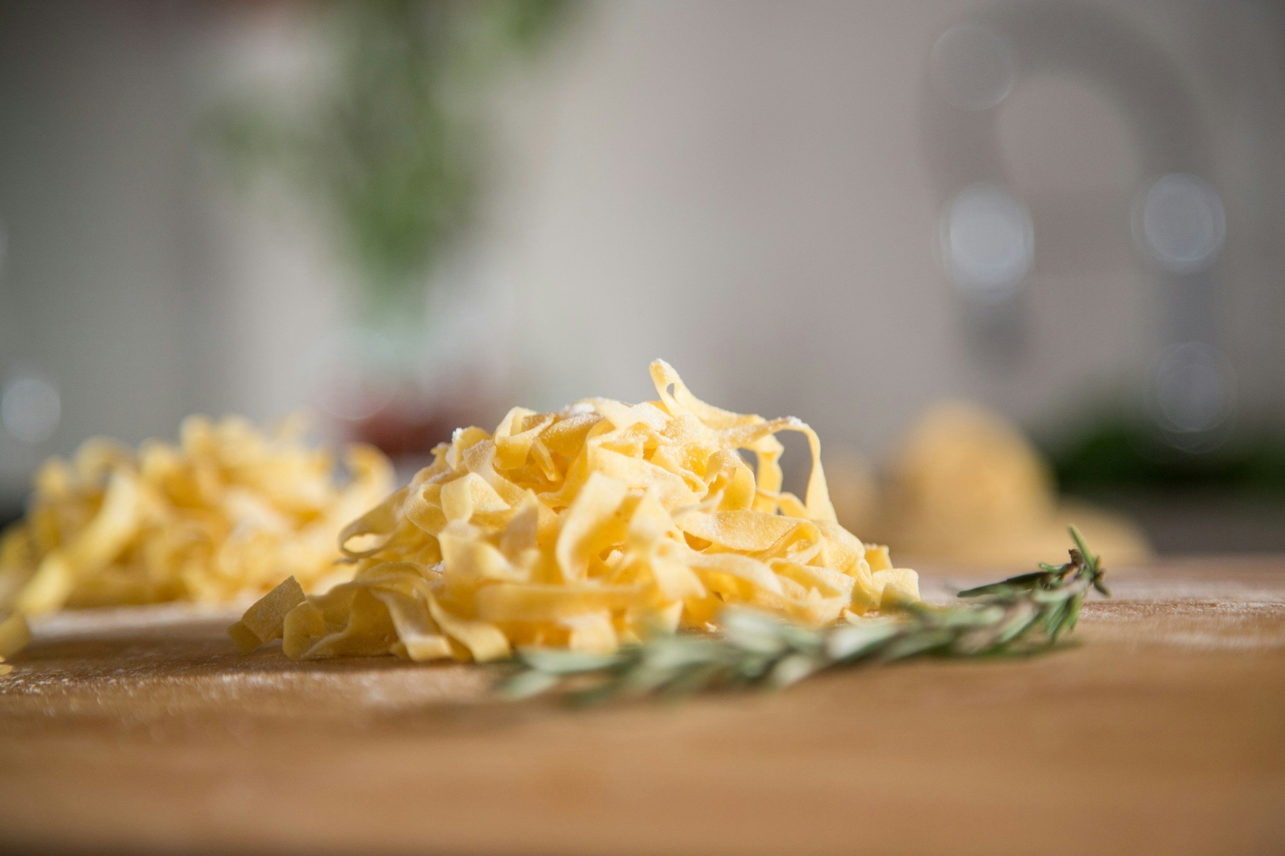 Close-up of shredded cheese on a wooden surface with sprigs of rosemary and a blurred background.