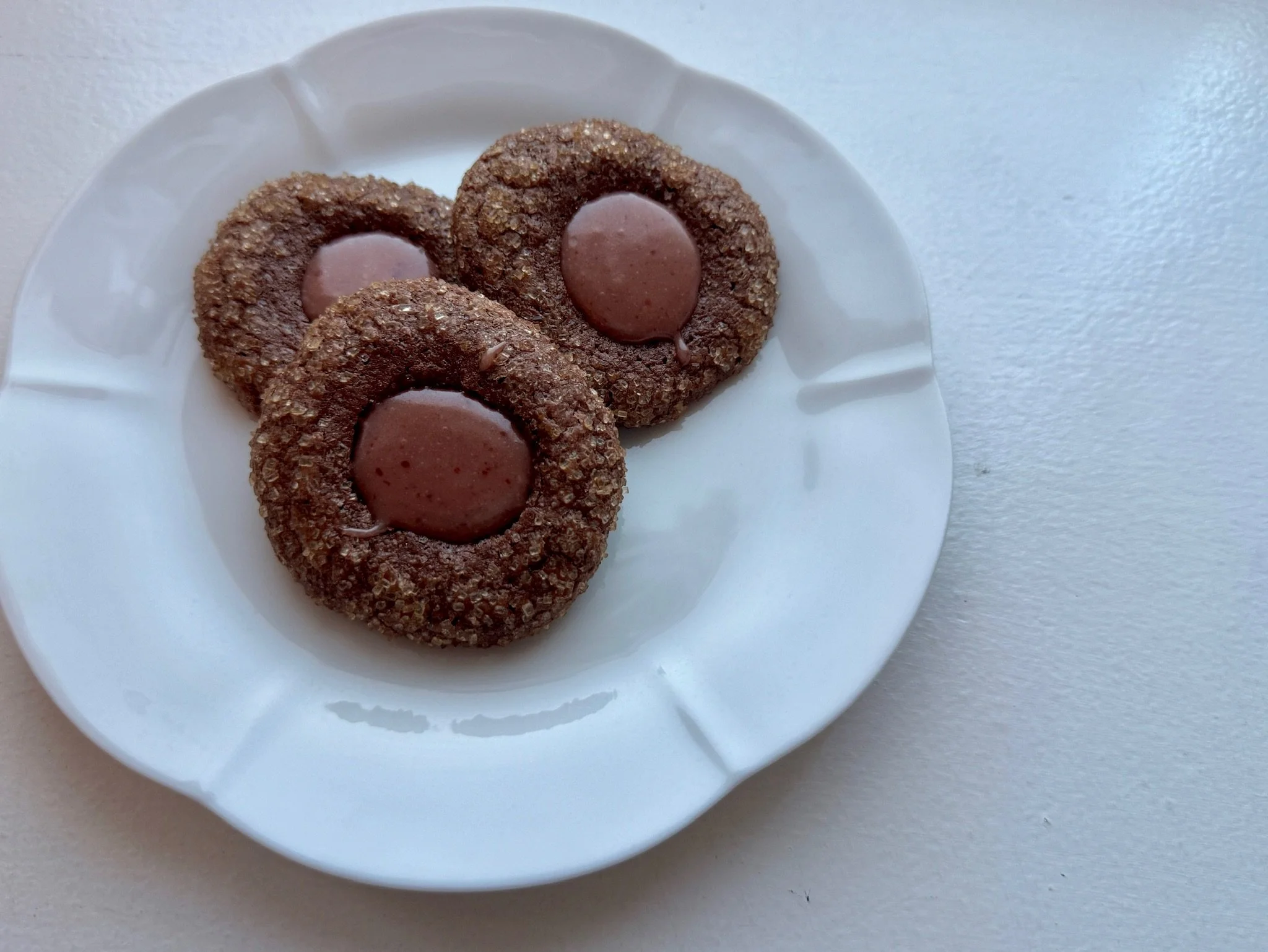 Three chocolate cookies with a glossy chocolate center on a white plate