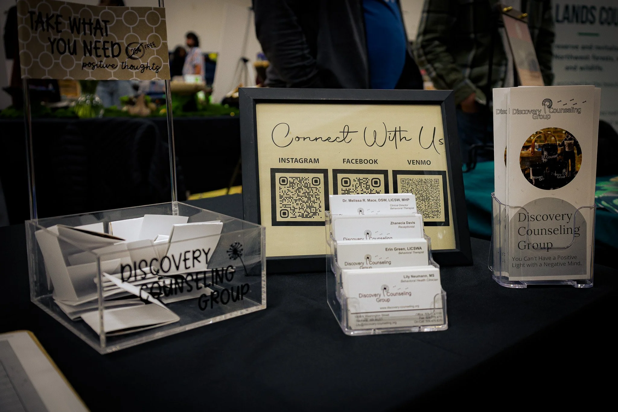 Display table with brochures, business cards, and a sign promoting connection through social media platforms, featuring QR codes for Instagram, Facebook, and Venmo, for the Discovery Counseling Group.