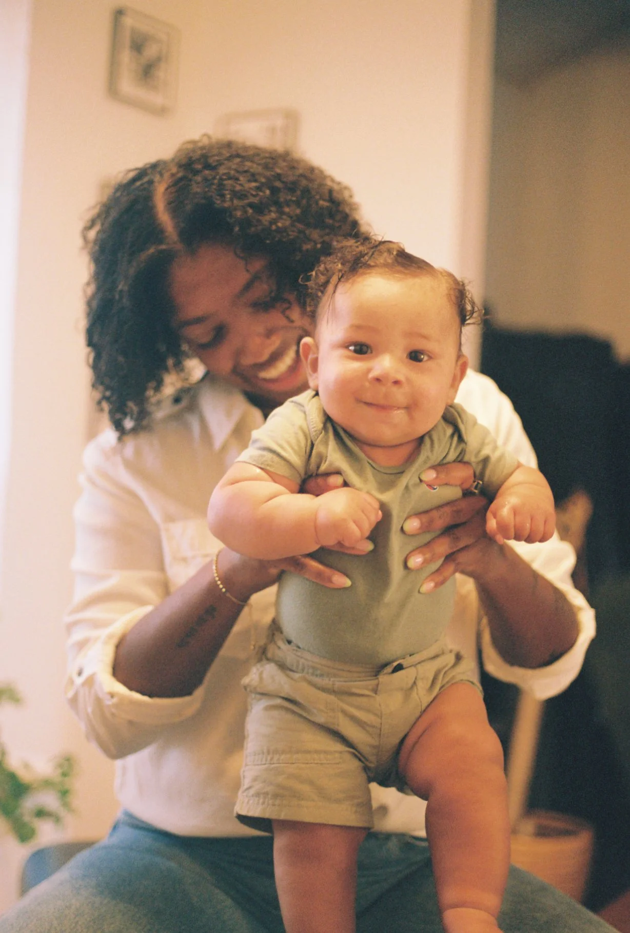 A woman holding a smiling baby boy in a home setting.