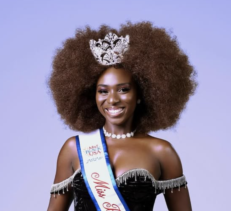 Miss Black Vermont 2026 winner with large curly hair wearing a tiara, sash, and off-the-shoulder black dress, smiling.