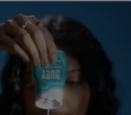 A person holding a bottle of Bounty paper towels over their face.