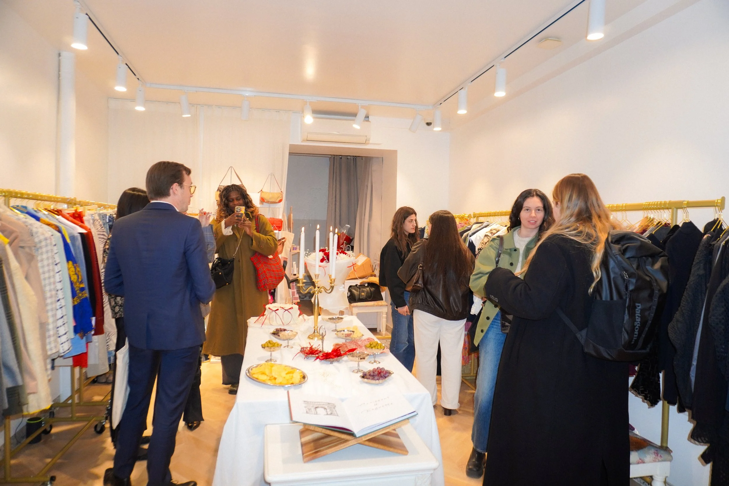 People shopping at a clothing store during a holiday event, with snacks and decorations on display.