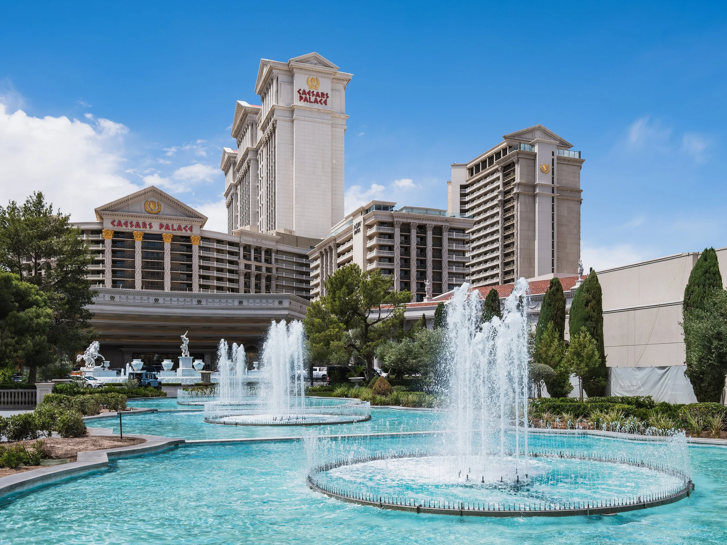 Les bâtiments du Caesars Palace à Las Vegas avec une fontaine en premier plan et un ciel bleu clair.