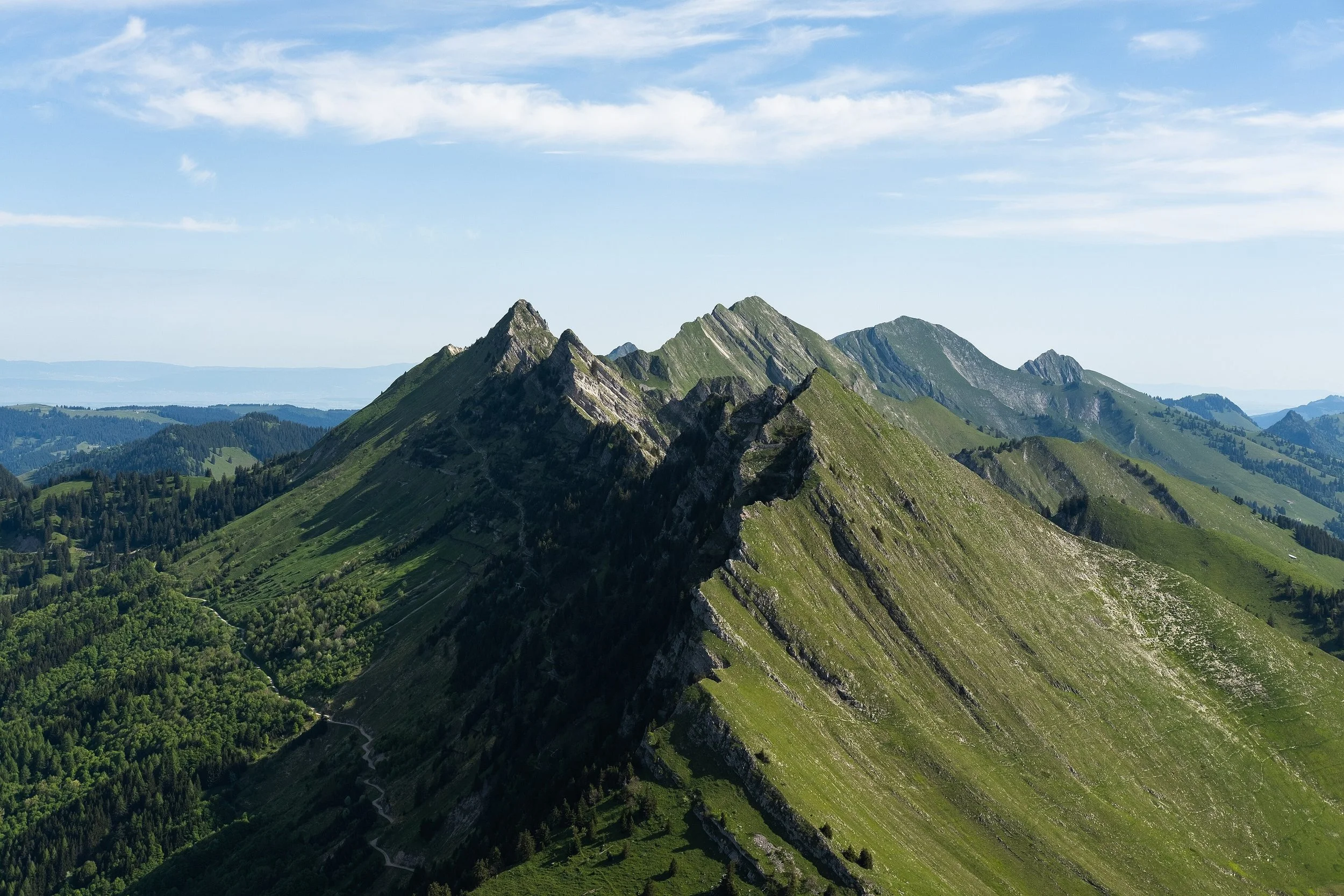 Montagnes verdoyantes sous un ciel bleu avec quelques nuages.