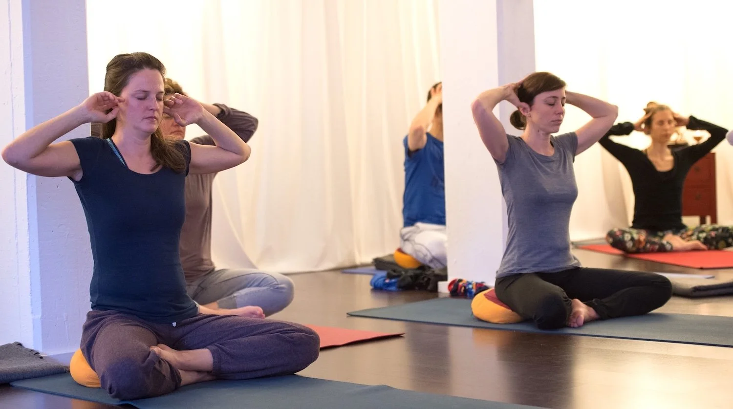 Eine Gruppe von Personen üben Yoga mit der Atemtechnik Pranayama Bienensummen Bhramarie
