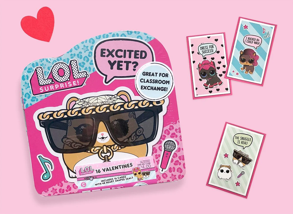 A pink box of LOL Surprise! Valentine cards featuring a cartoon dog wearing sunglasses and gold chain, with three small Valentine cards lying beside it on a pink background.
