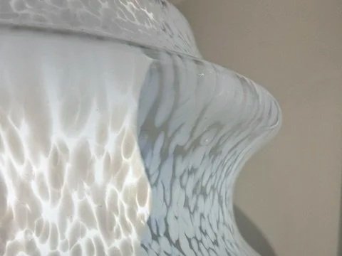 Close-up d'une sculpture ou d'une pièce en céramique blanche avec un motif texturé et des reflets lumineux.