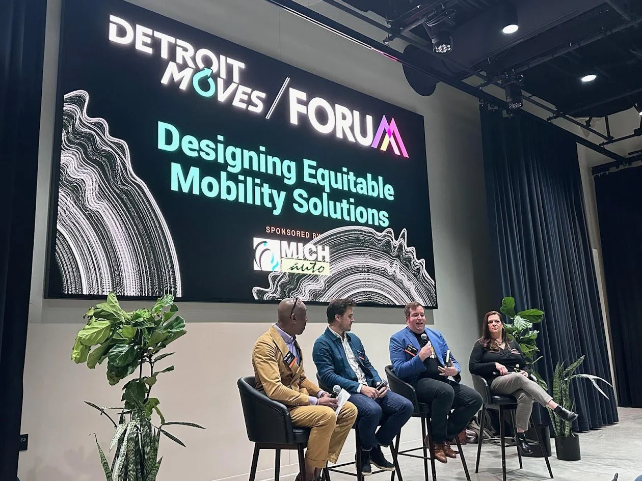 Alan Hejl speaking on a panel at the Detroit Moves Forum, seated alongside two gentleman and a woman.