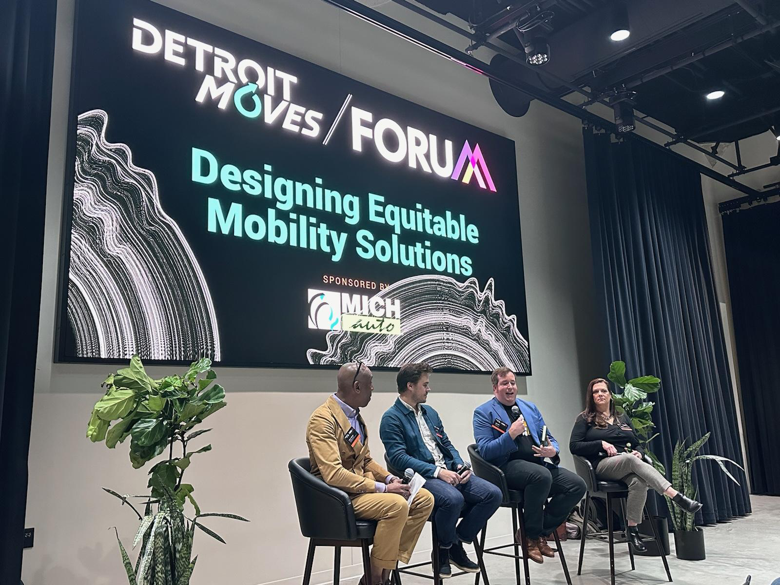 A photograph of Alan Hejl speaking on a panel at Detroit Moves Forum, speaking alongside two gentleman and one woman.