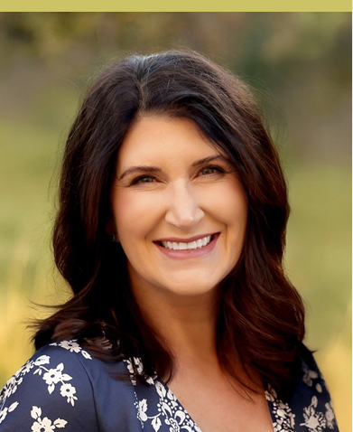 Toni's headshot, brown hair wearing a navy and white floral top, standing outdoors with blurred green background.