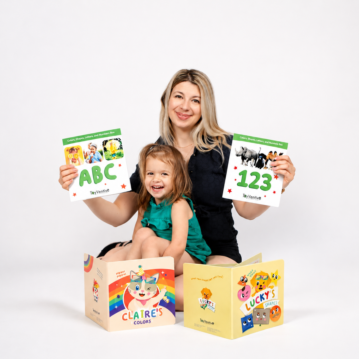 Mulher com filha pequena segurando livros infantis coloridos, uma com letras e números, outra com animais, na frente de um fundo branco.