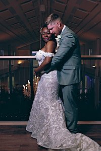 A couple dancing closely on a wooden floor at an indoor event, with warm lighting and blurred background.