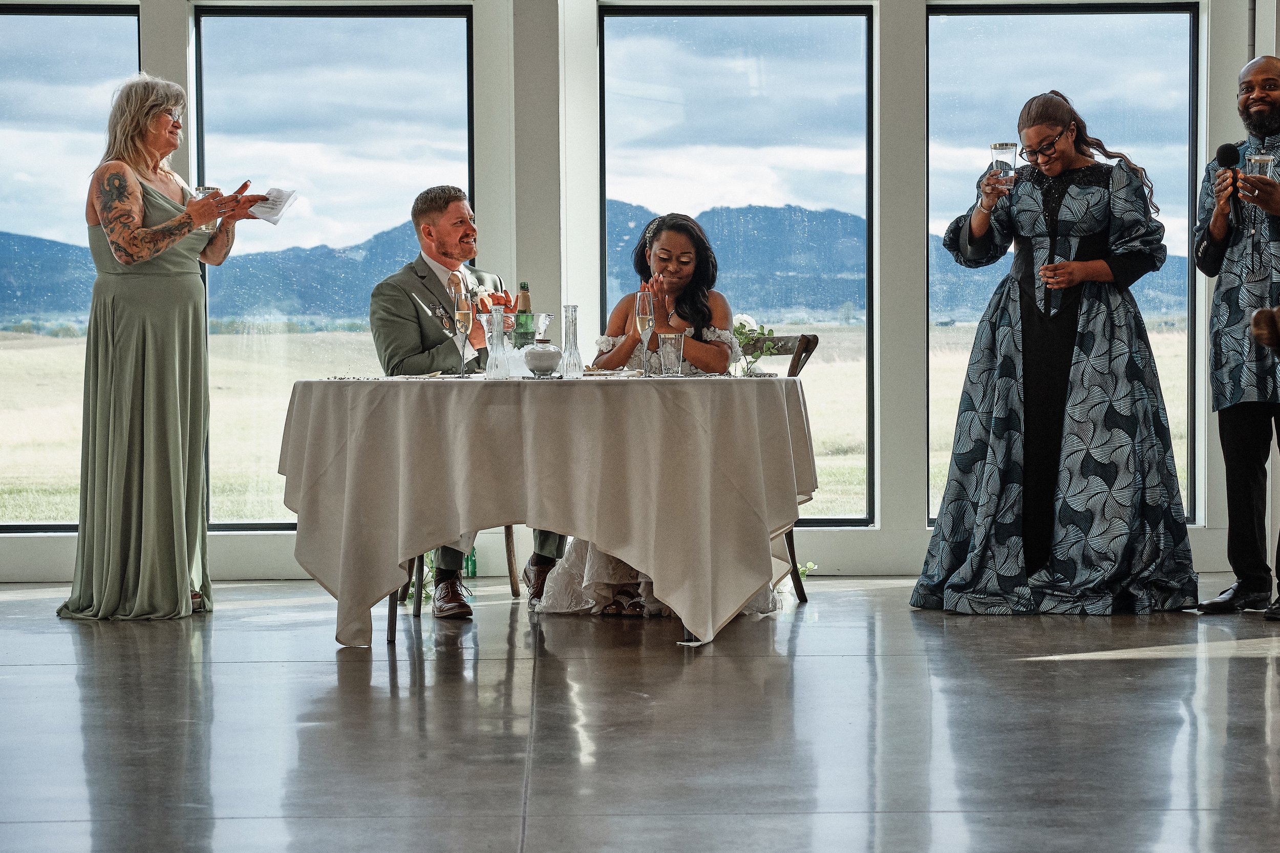 People attending a wedding ceremony inside with large window overlooking mountains