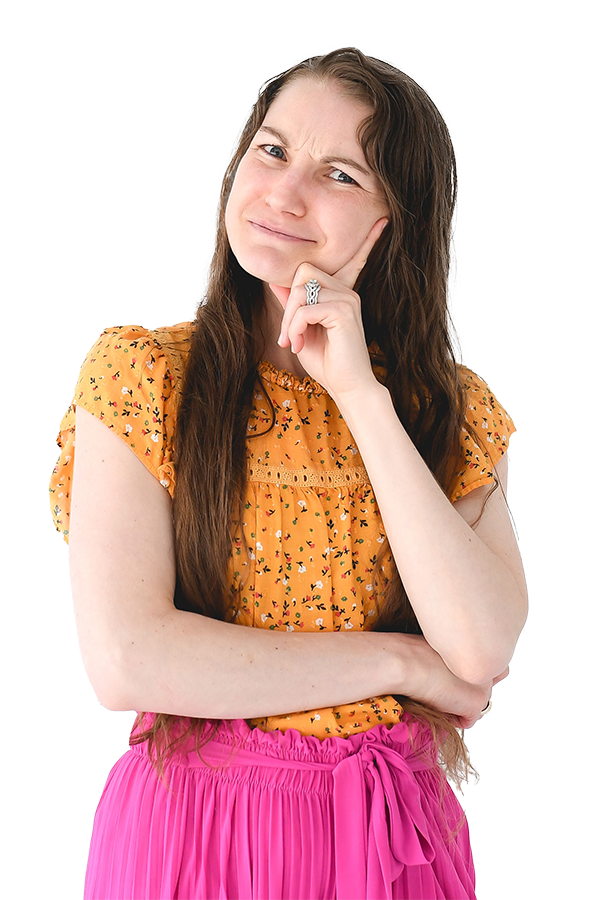 A young woman with long brown hair, wearing a yellow floral top and a pink skirt, standing with her arms crossed and a questioning expression, with her hand touching her chin.
