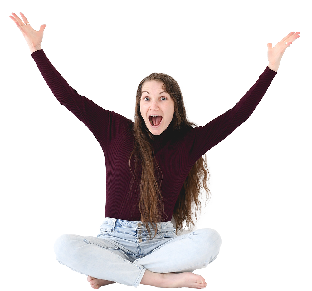 A woman sitting cross-legged with arms raised and a wide open mouth, expressing excitement or joy.