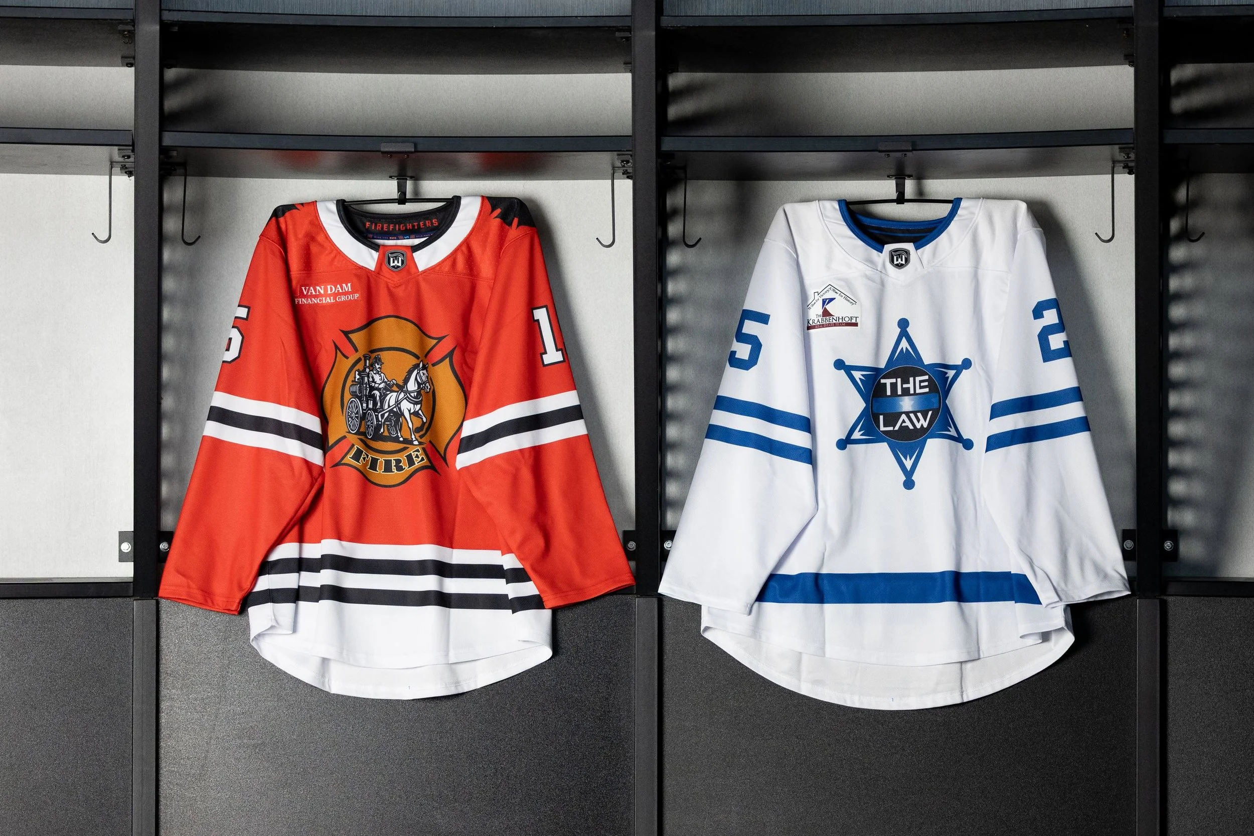 Two hockey jerseys hanging in a locker, one red and one white, with team logos and numbers.