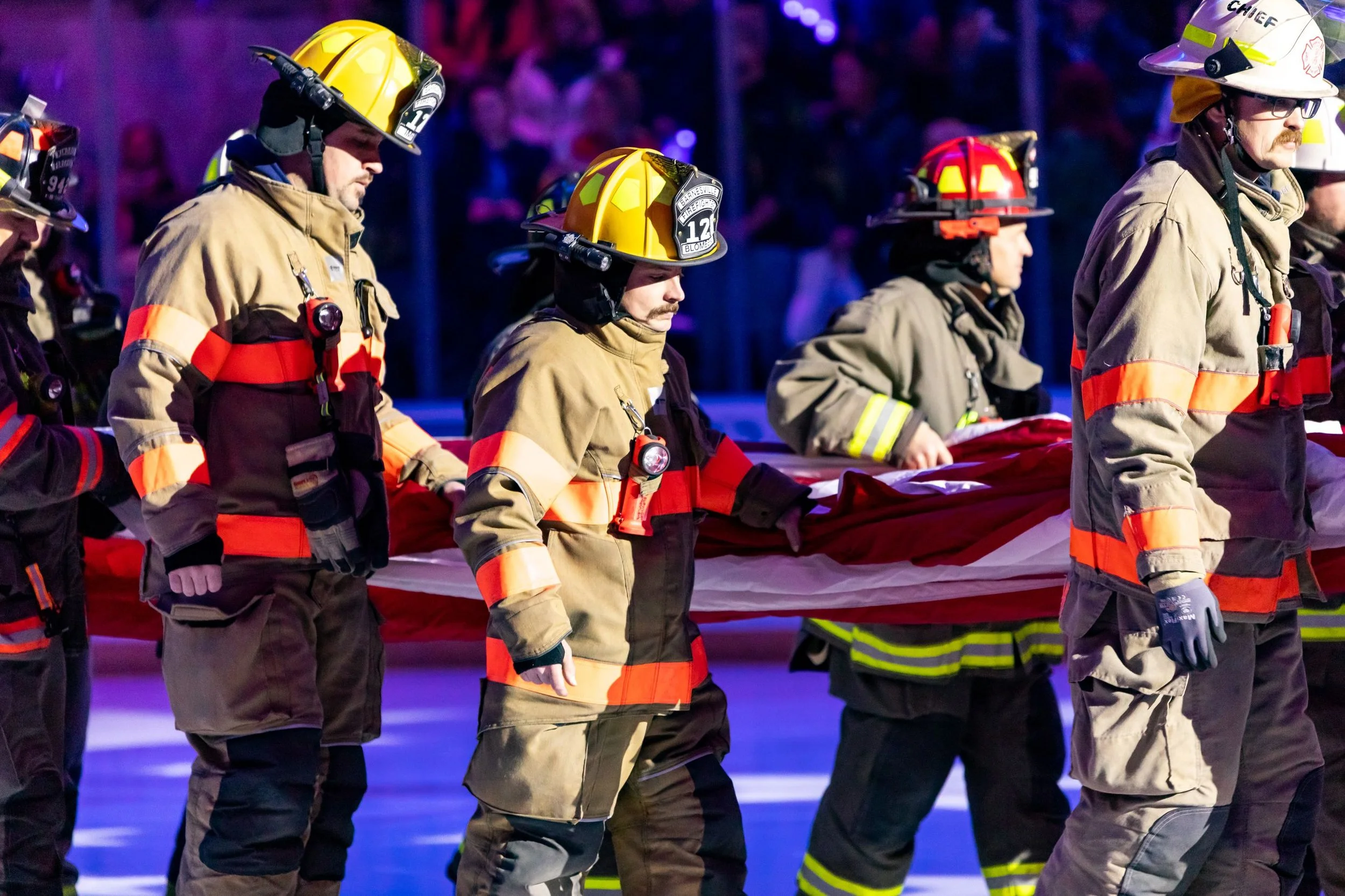 Firefighters carrying an American flag during a ceremony or commemoration event.