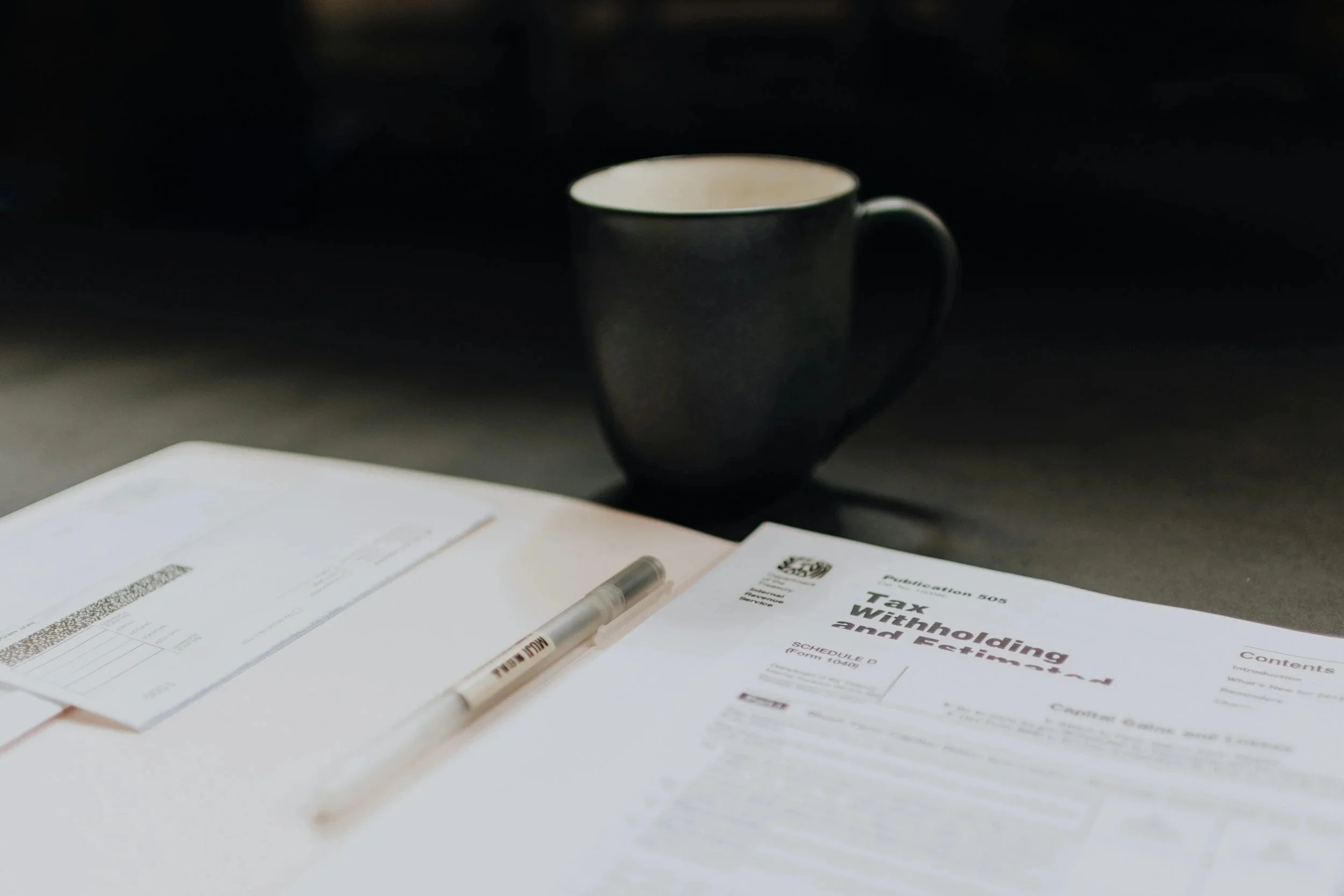 Legal documents and a pen on a table, with a black coffee mug in the background.