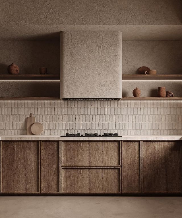 A minimalist kitchen with wooden cabinets, a white brick backsplash, and open shelves displaying ceramic pots and dishes. A beige range hood extends from the ceiling over a stovetop.