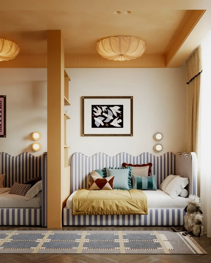 Living room with striped sofa, variety of colorful pillows, wall art of white birds, circular wall lights, and beige curtains by window.