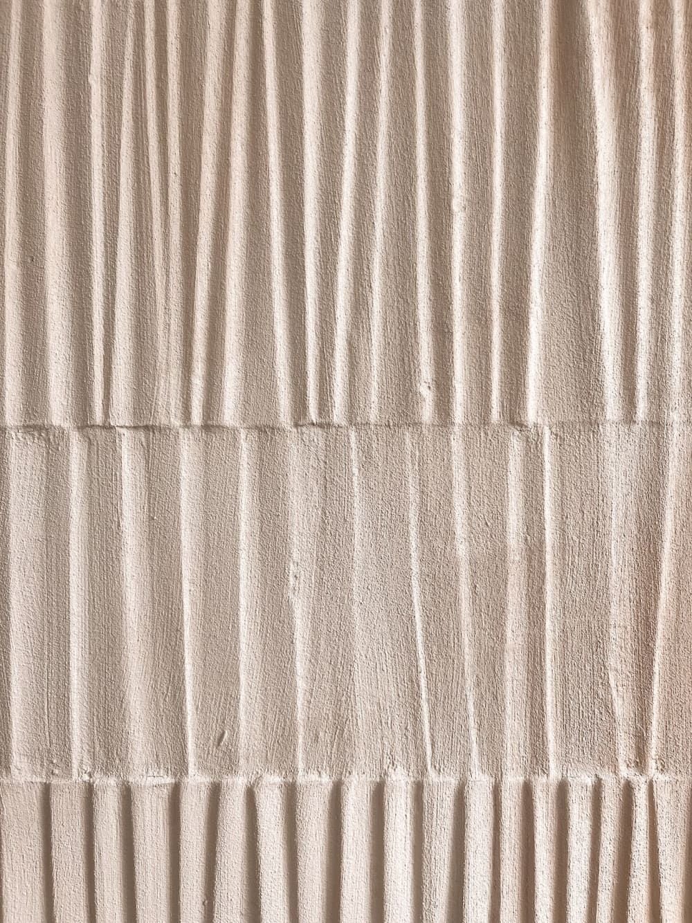 Close-up of a textured beige wall with vertical and horizontal grooves.