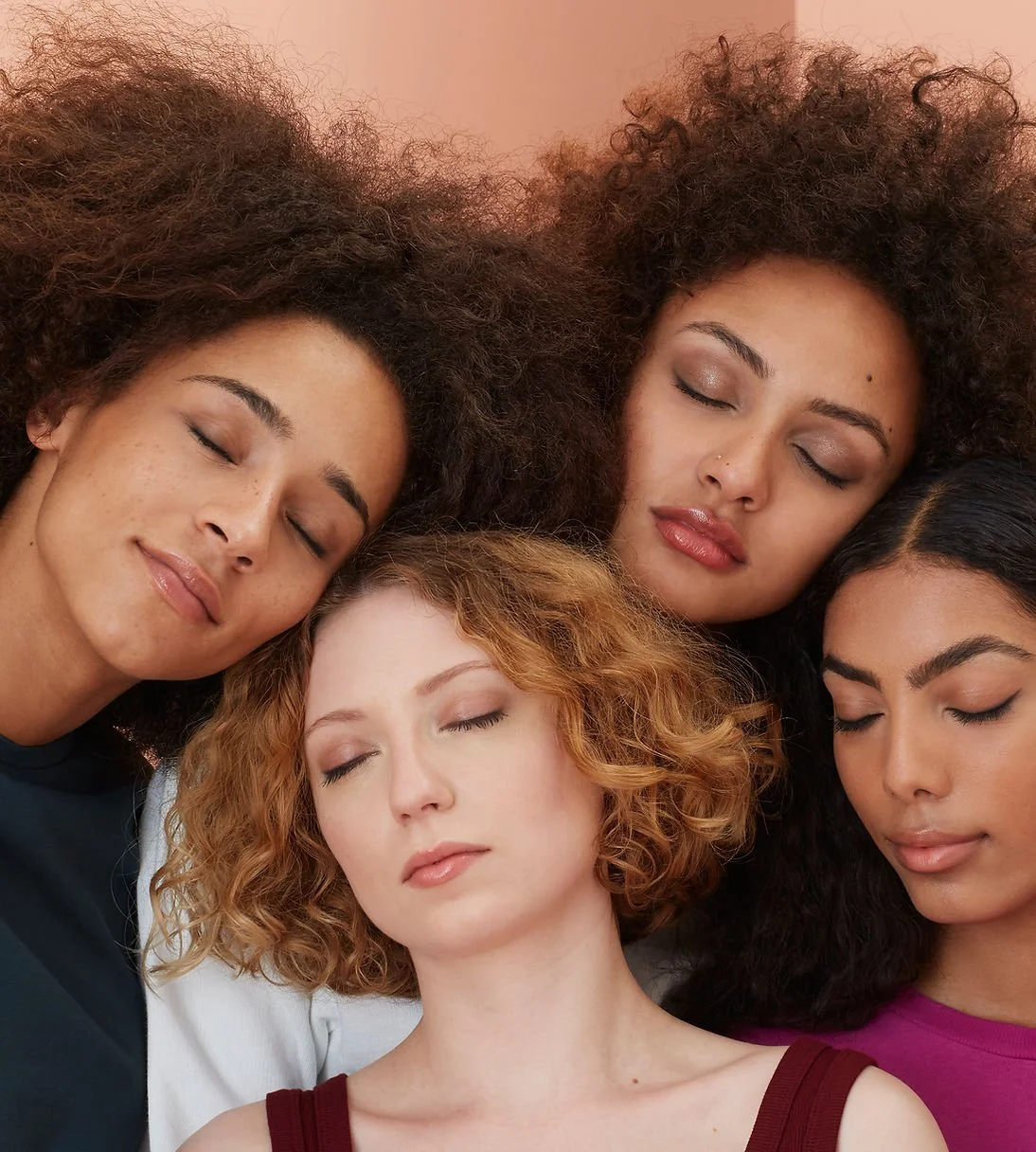 Four women with diverse hair types and colors relaxing with their eyes closed.