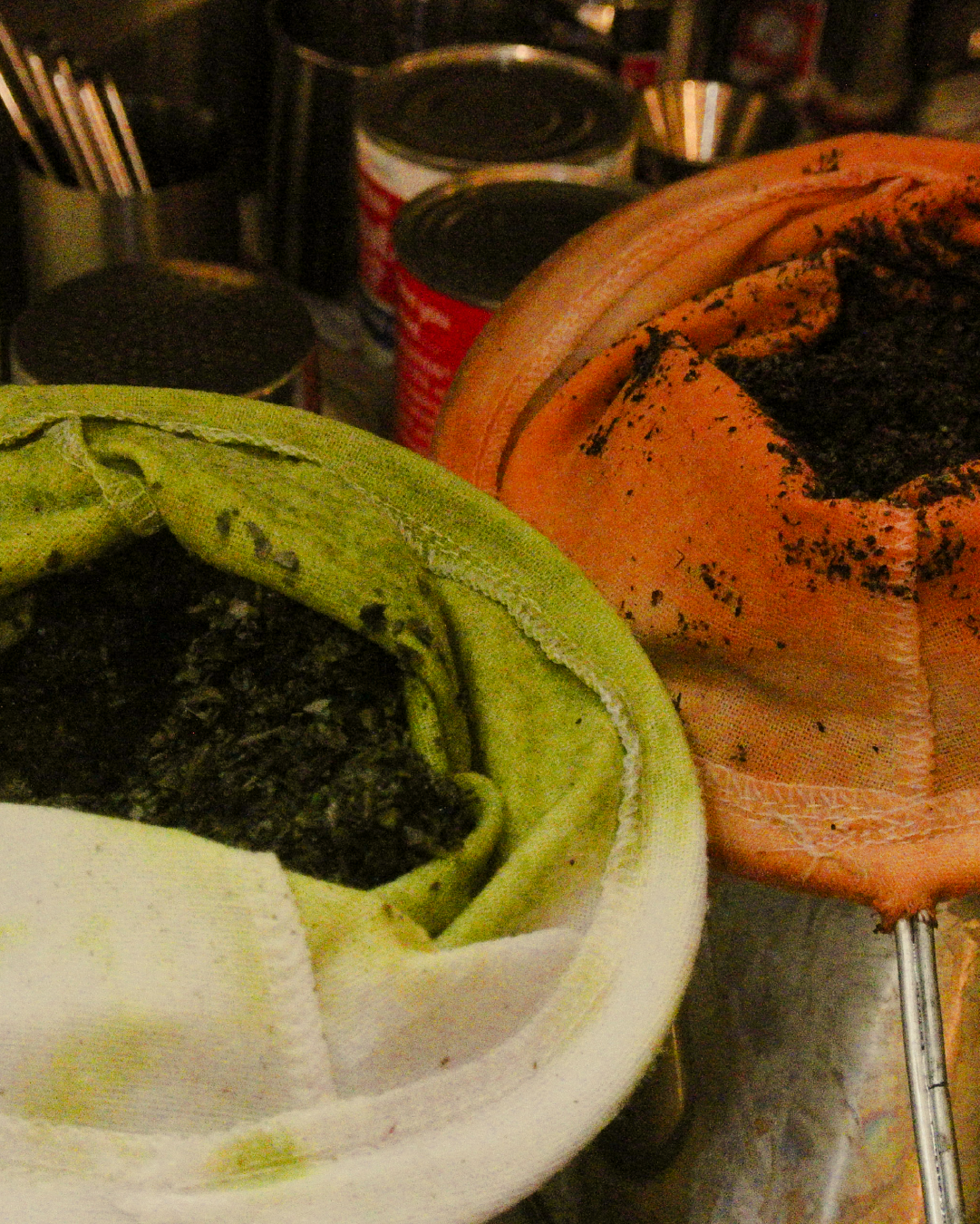 Close-up of traditional thai tea and thai green tea in cotton cloth filter bags, and cans of condensed milk in the background.